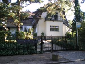 柏林Ferienwohnung Berlin的白色的房子,有黑色的栅栏和树木