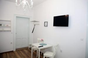 锡比乌Schick apartment的白色的用餐室配有桌子和墙上的电视