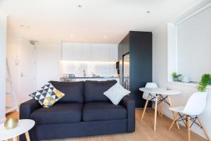奥克兰Brand New Auckland Apartment的一间带蓝色沙发的客厅和一间厨房