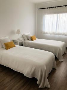 卡尔达斯达·赖尼亚Apartamento - Casas dos Infantes的白色客房的两张床,设有窗户