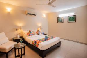 新德里沙克德阿努坦法布酒店的一间卧室配有一张床、一张沙发和一把椅子