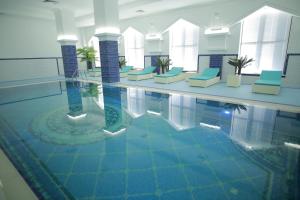 阿特劳苏丹皇宫酒店的一座游泳池,里面设有蓝色的椅子和水