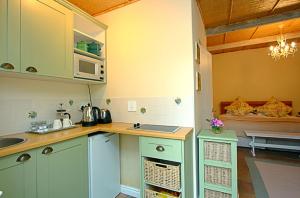 Tokai晨畔小屋宾馆的厨房配有绿色橱柜和台面