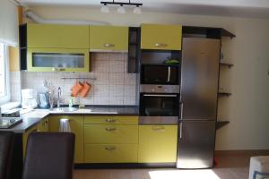 佩奇Árnyas apartman的厨房配有黄色橱柜和不锈钢冰箱
