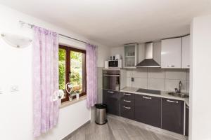 拉扎尼Villa Ana的厨房配有黑色橱柜和紫色窗帘