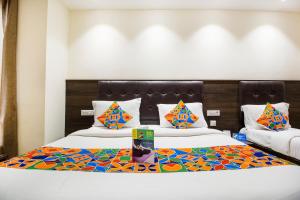 新德里FabExpress Le Continental的酒店客房配有两张带色彩缤纷枕头的床。
