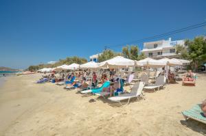 圣安娜纳克索斯Naxos Hostel的一群人坐在海滩上,拿着遮阳伞