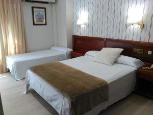 马林Hotel Villa de Marin的酒店客房设有两张床和两盏灯。