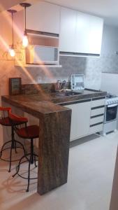 瓜拉派瑞Apartamento Ed. Ouro Preto Praia do Morro的厨房配有白色橱柜和带凳子的台面