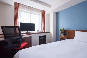 八王子市the b hachioji的酒店客房配有一张床和一张书桌及一台电视