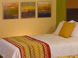 艾肯艾肯威士忌路万豪广场套房酒店的墙上有三幅画作的房间的一张床位