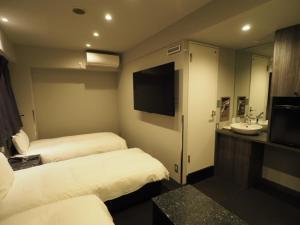 东京羽田旅馆的酒店客房设有两张床、一个水槽和电视。