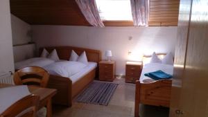SandWeinhotel Goger的一间小卧室,配有两张床、一张桌子和一个窗户