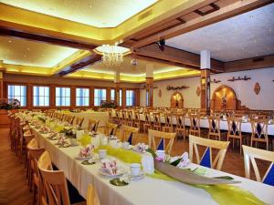 SandWeinhotel Goger的一个带白色桌椅的大型宴会厅