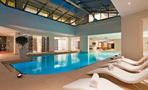 普拉塔尼亚斯普拉塔尼亚斯港海滩度假酒店及Spa中心的酒店游泳池设有白色椅子和蓝色游泳池