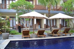 坎古黛比麦都宾馆的一组椅子和遮阳伞,位于游泳池旁