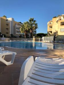 滨海卡涅Front beach Luxury near Nice airport的一座大型游泳池,在大楼里设有白色长凳