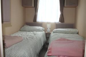 彭布罗克郡The Valley Static Caravan的配有2张床的小卧室设有窗户
