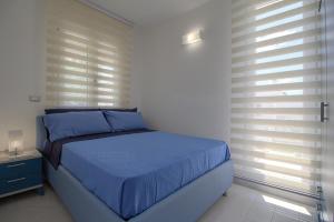 莱乌卡Greg Bay的一间卧室配有一张带蓝色床单和窗户的床。