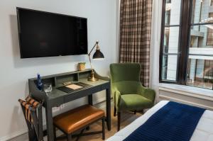 纽约Merrion Row Hotel and Public House的客房设有书桌、电视和椅子。