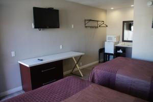 长滩海滩旅馆汽车旅馆的酒店客房设有一张桌子和一台墙上的电视。