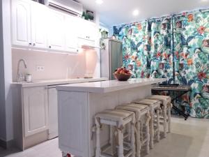 多列毛利诺斯Aloha Paraíso的厨房配有白色橱柜和带凳子的台面