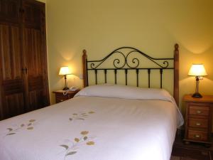 Barajas de GredosHotel Rural La Dehesilla的一间卧室配有一张带两盏灯的大型白色床。