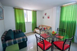 圣玛尔塔El Velero Apartamentos By DANP的客厅配有绿色窗帘和玻璃桌及椅子
