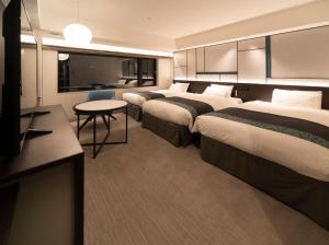 大阪Hotel Vischio Osaka-JR Hotel Group的酒店客房设有三张床和电视。
