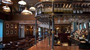 米尔盖West Highland Apartments Milngavie - The Lomond的酒吧设有木桌和酒杯