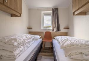 SkarsvågSeaside cabin Skarsvåg的一间卧室配有两张床和椅子