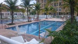曼加拉蒂巴Loft com Praia的一座游泳池,里面摆放着椅子和棕榈树