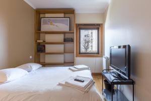 波尔图Deluxe Condominium with Ocean View的一间卧室设有一张床、一台电视和一个窗口。