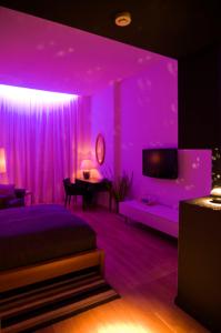 奥拉迪亚Ivana Apart Hotel的紫色客房,配有一张床和一台电视机