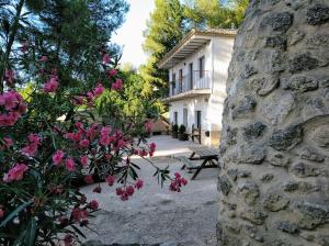 巴尔德甘加Casa Rivera Río Jucar的一座石墙和粉红色花卉的房子
