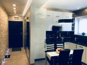 扎布热Apartament Ala的厨房配有白色橱柜和桌椅