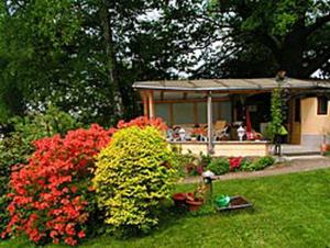 RathmannsdorfHaus Grüllich的花园种有红色的鲜花,设有凉亭