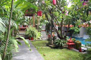 清迈塔帕别墅酒店的花园拥有红色灯笼和树木,设有游泳池