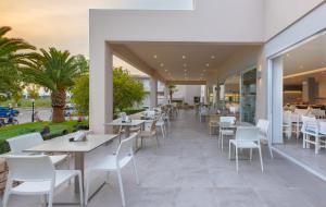 马尔马里Hotel Esperia的一间设有白色桌子和白色椅子的餐厅