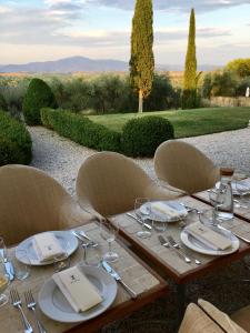 PozzoFontelunga Hotel & Villas的一张木桌,配有椅子和盘子,酒杯