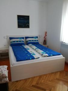 圣马丁娜穆里Apartmani Oletić 4*的一张白色的床,上面有蓝色的床单和枕头