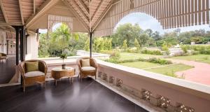 班加罗尔泰姬西尾酒店的一个带椅子的门廊,享有花园的景色