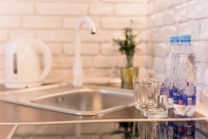 弗罗茨瓦夫GoldenEye Apartment Center的厨房柜台设有水槽和2瓶及玻璃杯