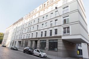 弗罗茨瓦夫GoldenEye Apartment Center的一座白色的建筑,前面停有两辆车