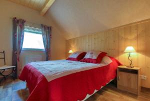 奥斯泰姆Gite au pré des Oies的一间卧室配有一张带红色和白色床单的大床
