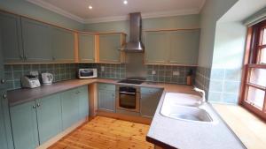 巴洛赫Smiddy Lodge的厨房配有蓝色橱柜和水槽