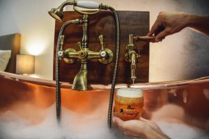 布拉格乌迷得维库啤酒酒店的一个人在浴缸里拿着一杯啤酒