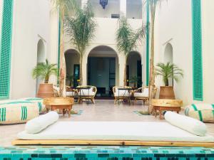 马拉喀什Riad Alia的一座带桌椅和棕榈树的游泳池