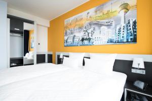 杜塞尔多夫杜塞尔多夫克拉特城市酒店的卧室配有一张床,墙上挂有绘画作品