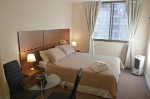圣地亚哥Origen Apart-Hotel的一间卧室配有一张带桌子和窗户的床